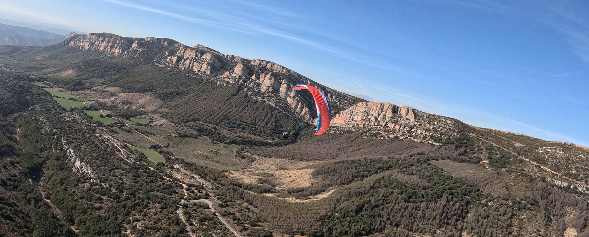 Vue aérienne d'un parapente survolant les paysages montagneux et vallonnés d'Ager, en Espagne, par une journée ensoleillée
